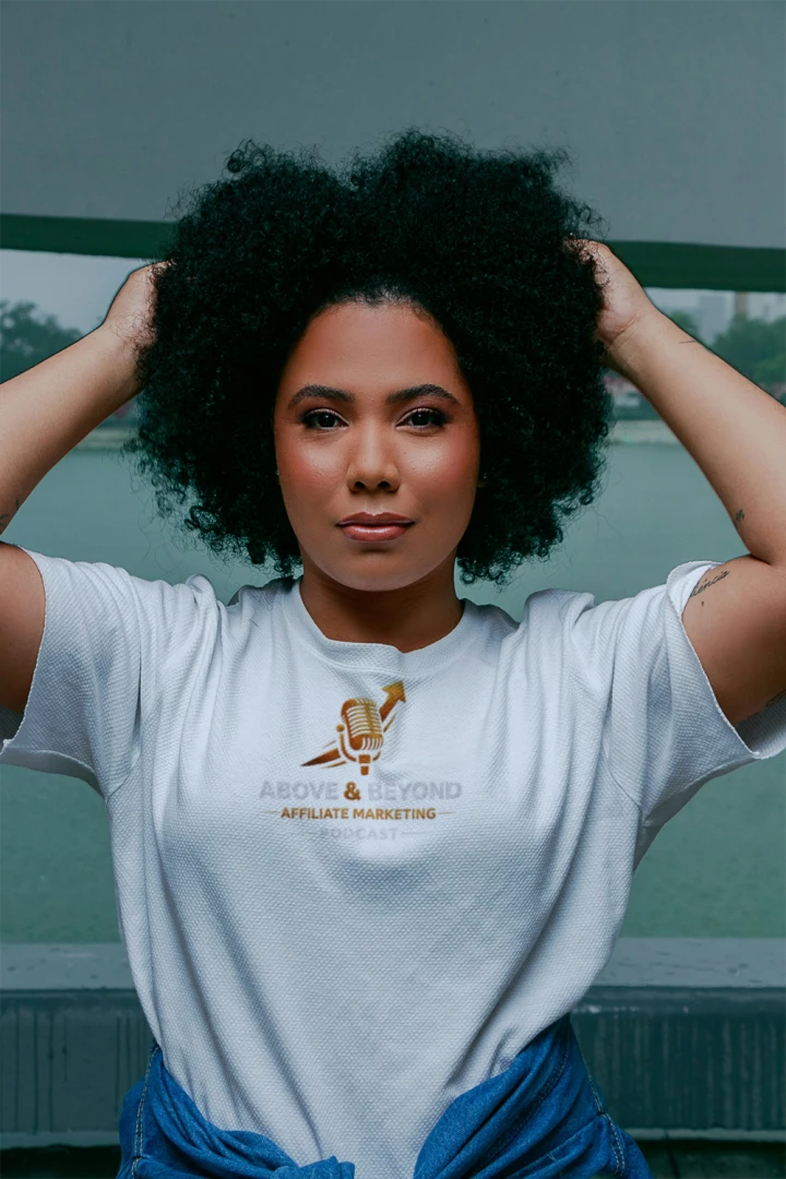 Woman wearing a white t-shirt with Above and Beyond Affiliate Marketing Podcast logo text and graphics, standing outdoors.